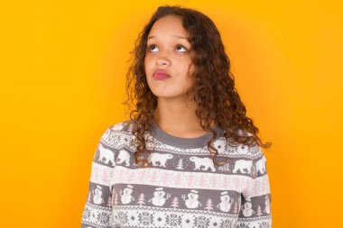 Tatminsiz bir kadın Noel süveteri giyiyor sarı stüdyo arka plan çantaları dudakları ve mutsuz bakışları var gücenmiş duruyor. Bunalımlı model.