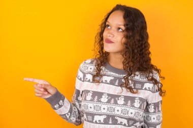  Noel süveteri giyen bir kadın fotokopi stüdyosunda sarı arka plan noktaları ve reklam gibi bir şey, en uygun fiyat öneriyor..