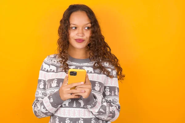 Glückliche Frau Trägt Weihnachtspullover Gegen Gelben Studiohintergrund Und Hört Musik — Stockfoto