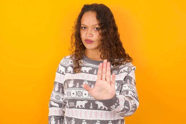 Frau Weihnachtspullover Vor Gelbem Studiohintergrund Zeigt Stoppschild Verbotssymbol Hält Handfläche — Stockfoto