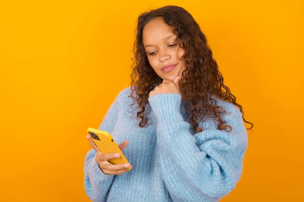 Thoughtful Happy Curly Woman Wearing Blue Sweater Yellow Studio Background — Stock Photo, Image