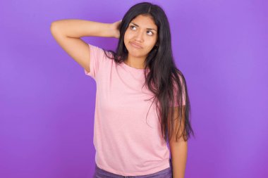 Mor arka planda pembe tişört giyen esmer İspanyol kız soru sormayı merak ediyor. Şüpheyle kararsız, kafa kafaya düşünerek. Düşünceli kavram.