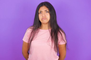 Mor arkaplan üzerine pembe tişört giyen esmer, mutsuz, hoşnutsuz ve amaca ulaşamadığı için ağlayacak yüz ifadesi takındı. Hayal kırıklığına uğramış modelin sorunları vardır.