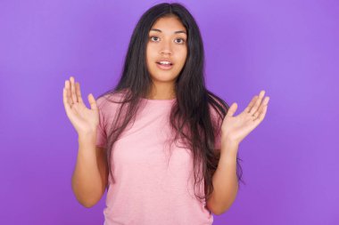Mor arka planda pembe tişört giyen esmer kız şaşırmış. Belirsizlikle jestler yapıyor, kameraya bakıyor. Şaşırtıcı soruya cevap veremiyor. 