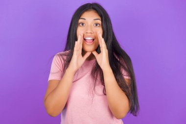 Pembe tişörtlü esmer kız mor arka planda heyecanla bağırıyor.. 