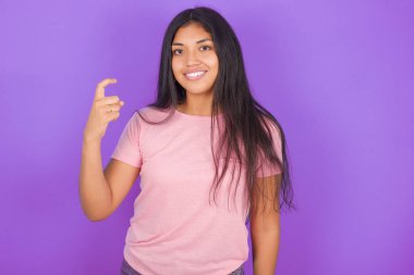 Mor arkaplan üzerine pembe tişört giyen esmer İspanyol kız Çince işaret diliyle 