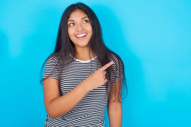 Mavi arka planda çizgili tişört giyen İspanyol genç kız fotokopi alanını gösteriyor.