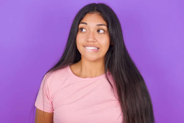 素晴らしいですヒスパニック系ブルネット女の子身に着けていますピンクTシャツ以上紫の背景ビッティングクリップと探してトリッキーなへ空のスペース — ストック写真