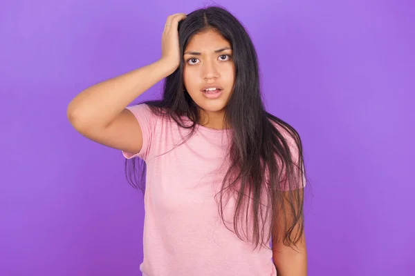 恥ずかしいヒスパニック系のブルネットの女の子はショックを受けた式で紫の背景にピンクのTシャツを着て 大きな驚きを表現し パズルモデルは屋内ポーズ — ストック写真