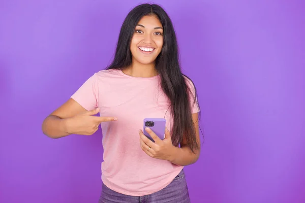 Chica Morena Hispana Vistiendo Camiseta Rosa Sobre Fondo Púrpura Sosteniéndose —  Fotos de Stock