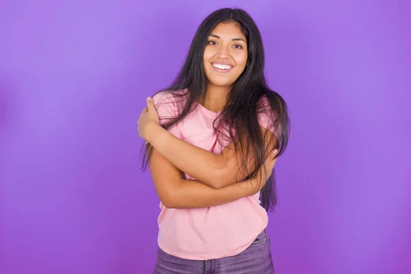 迷人的青春惊慌失措的女孩穿着粉色T恤 背景紫色 拥抱自己的身体 愉快地感觉到舒适的姿势 温柔和自尊的概念 — 图库照片
