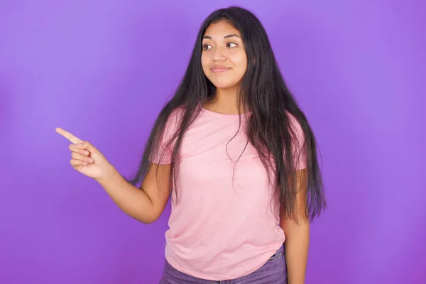 若いですヒスパニック系の女の子身に着けていますピンクTシャツ以上紫背景ポイントでコピースペースと広告何か 助言ベスト価格 — ストック写真