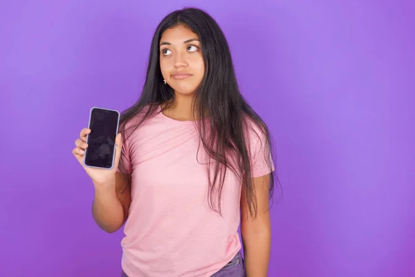 Joven Chica Hispana Vistiendo Camiseta Rosa Sobre Fondo Púrpura Sostiene —  Fotos de Stock