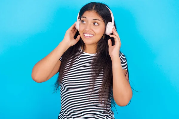 Mladá Hispánka Pruhovaném Tričku Modrém Pozadí Nosí Stereo Sluchátka Poslouchá — Stock fotografie