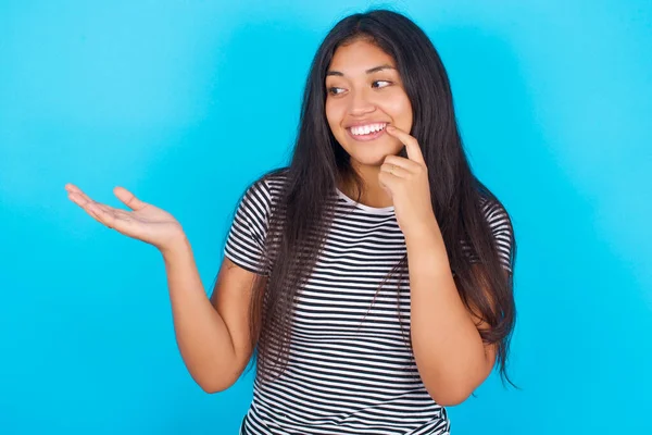 Positive Young Hispanic Girl Wearing Striped Shirt Blue Background Adverts — Stock Photo, Image