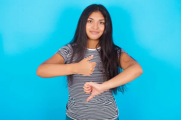 Молодая Латиноамериканка Полосатой Футболке Синем Фоне Показывает Большой Палец Вверх — стоковое фото