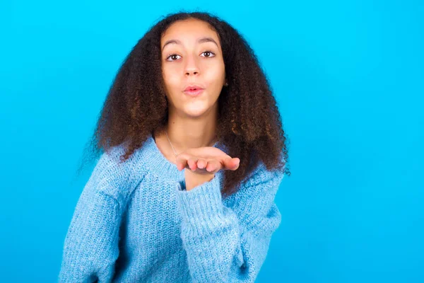 非洲裔美国少女 身穿蓝色背景的蓝色毛衣 头戴非洲式发式 看着摄像机 与空气中的一个吻是可爱和性感的 爱的表达 — 图库照片