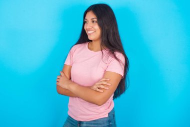  El ele tutuşup fotokopi çeken bir kadın. Pembe tişört giyen esmer, güzel bir kadın mavi arka plana poz veriyor.