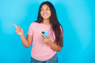 Vay canına! Heyecanlı genç, güzel Latin kız cep telefonunu gösteriyor ve işaret ediyor. 