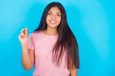  Kız elini göstererek işaret ediyor. Çince işaret dili Q 'da yedi parmak hareketi gösteriyor. Pembe tişört giyen esmer, güzel bir kadın mavi arka plana poz veriyor.