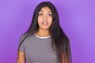 Mor arka planda, çizgili tişörtlü, güzel, Latin bir kadın.