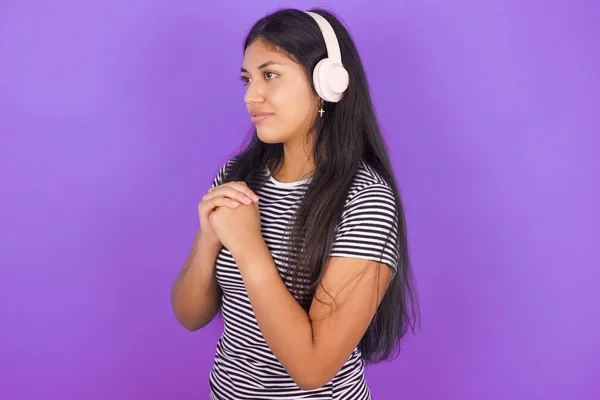 ストライプTシャツを着ている若いラテン系女性は 音楽に集中して興味を持って見ているステレオヘッドフォンを着用します — ストック写真