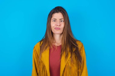 Mavi stüdyo arka planında ceket giyen genç ve güzel bir kadın gözlerini kırar, dudaklarını büzüştürür, garip bir ifadeyle yüzünü buruşturur tek başına eğlenir, aptalı oynar..