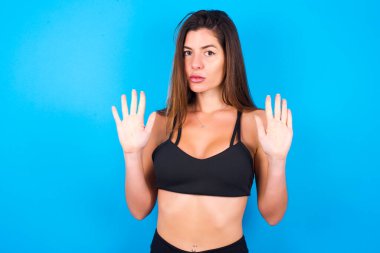 Güzel esmer kadın spor giyer, avuç içiyle şarkı söylemeyi keser. Yüzünde olumsuz ve ciddi bir jest olan uyarı ifadesi.