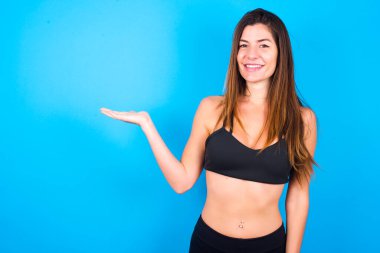 Spor giyim kuşamı giyen güzel esmer kadın diyor ki: Vay be, ne kadar heyecan verici, hayret verici bir ifade, boş uzayda boş elle bir şey gösteriyor. Reklam kavramı.