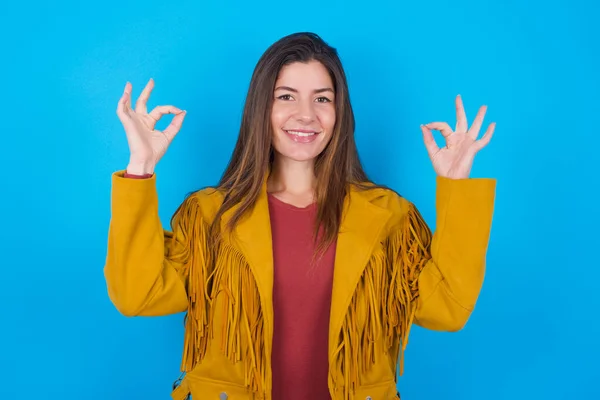 Щаслива Жінка Куртці Над Синім Студійним Фоном Показує Знак Добре — стокове фото