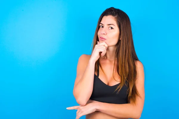 woman with hand under chin and looking sideways with doubtful and skeptical expression, suspect and doubt.