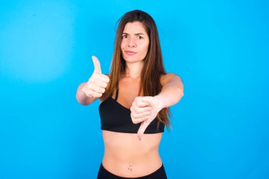 Güzel esmer kadın spor giysisi giyiyor. Emin değil. İyinin kötüye işaret olduğunu düşünüyor. Memnun değil ve etkilenmemiş..