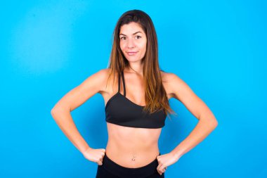 Komik, hayal kırıklığına uğramış, güzel esmer kadın spor kıyafetleri giyiyor, el ele tutuşuyor ve garip bir duruma bakıyor..