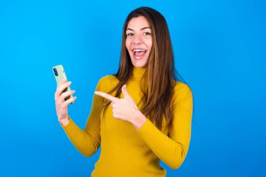 Mavi arka planda sarı süveter giyen güzel bir kadın inanılmaz derecede beklenmedik bir uyarı tavsiyesini etkiledi.