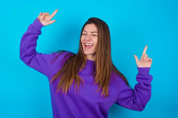 Photo Upbeat Beautiful Woman Wearing Purple Sweater Blue Studio Background — Stock Photo, Image