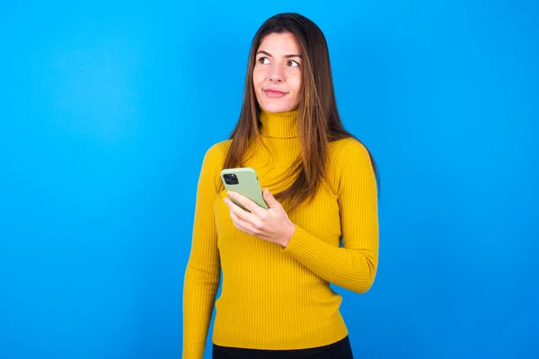 Young Beautiful Woman Wearing Yellow Sweater Blue Studio Background Holds — Stock Photo, Image