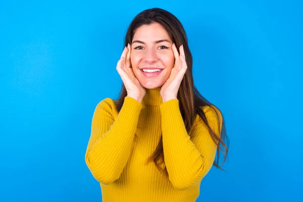 Happy Young Woman Wearing Yellow Turtleneck Sweater Touches Both Cheeks — Stock Photo, Image