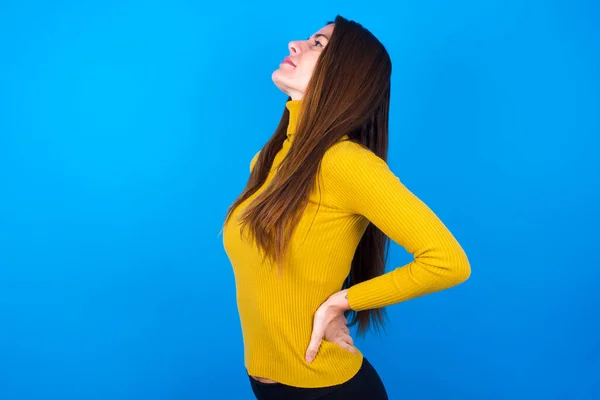 Junge Schöne Frau Gelbem Pullover Über Blauem Studiohintergrund Bekam Rückenschmerzen — Stockfoto