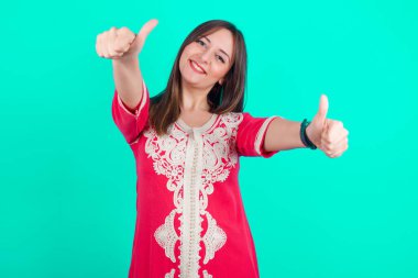 Genç, beyaz, güzel bir kadın elleriyle olumlu bir jest yapmayı onaylıyor. Başparmağıyla gülümsüyor ve başarı için mutlu. Kazanan jest.