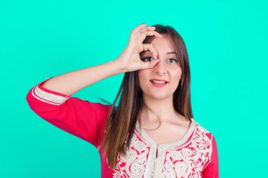 Genç, güzel, beyaz bir kadın. El hareketleriyle gülümsüyor. Gözleri, mutlu yüzüyle parmaklarının arasından bakıyor..