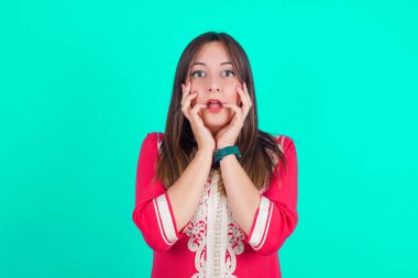 Heyecan ve heyecan ifade eden şaşkın bir kadın, çenesi düşük, elleri yanaklarında, gözleri fırlamış