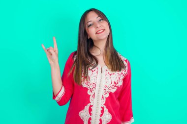 Genç, beyaz, güzel bir kadın kameraya gülümsüyor. En sevdiği konsere gitmeye hazır..