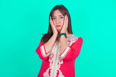 Elleri yüzü, depresyonu ve üzüntüyü örten yorgun, genç, beyaz bir kadın.