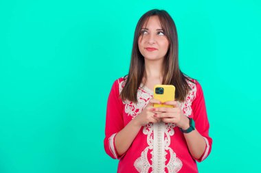 Genç, güzel, beyaz bir kadın elinde akıllı bir telefonla iyi haberler okuyor.