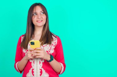 Genç, güzel, beyaz bir kadın elinde akıllı bir telefonla gençlik haberleri okuyor. 