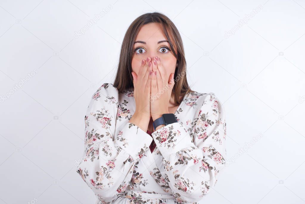 young beautiful woman wearing floral dress over white background is surprised  in studio