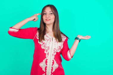 Genç, beyaz bir kadının kafası karışmış ve avuç içinin açık olmasından rahatsız olmuş. Kopya alanını gösteriyor ve alnını işaret ediyor. Bunu bir düşün..