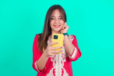 Neşeli kadın cep telefonu cihazıyla poz veriyor, modern akıllı telefona mesaj yazıyor, boş zamanlarında komik videolar izliyor, iyi internet bağlantılarından hoşlanıyor,