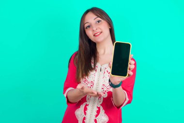 Akıllı telefonlu güzel, beyaz bir kadın. Akıllı telefonu sunuyorum. Reklam kavramı.