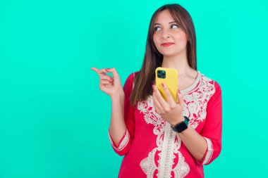 Vay canına! Heyecanlı genç beyaz kadın cep telefonunu açık el hareketleriyle gösteriyor.